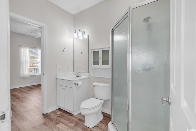 bathroom with a shower with door, vanity, hardwood / wood-style floors, and toilet