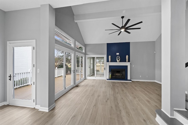 unfurnished living room featuring a fireplace with raised hearth, ceiling fan, baseboards, french doors, and light wood-type flooring