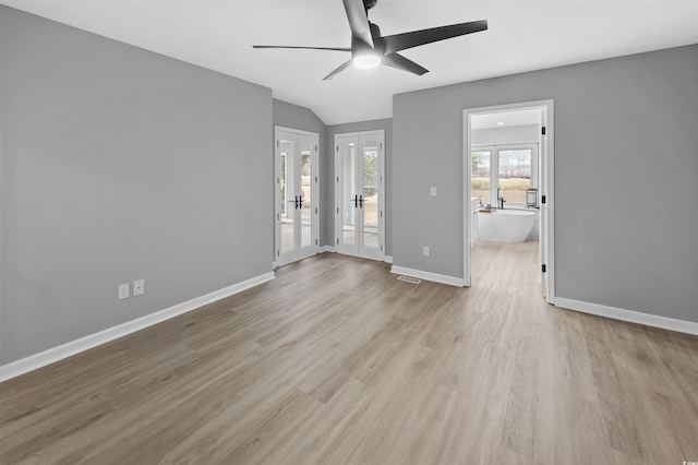 empty room featuring visible vents, a ceiling fan, vaulted ceiling, wood finished floors, and baseboards