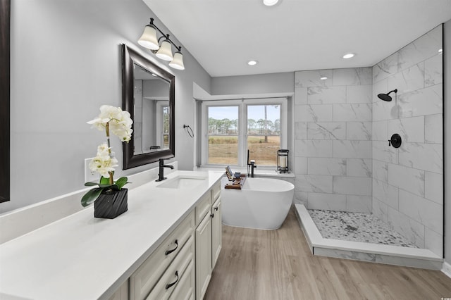 full bathroom featuring recessed lighting, wood finished floors, vanity, tiled shower, and a soaking tub