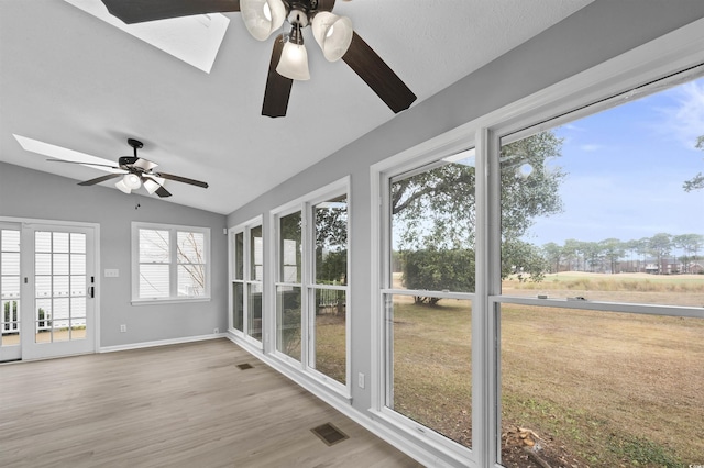 unfurnished sunroom with ceiling fan and vaulted ceiling with skylight