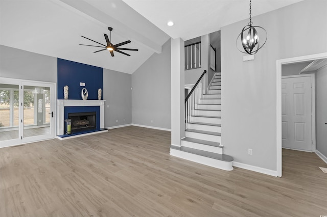 unfurnished living room with a fireplace with raised hearth, stairway, and wood finished floors