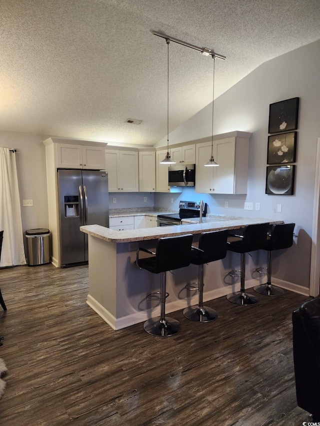 kitchen featuring kitchen peninsula, a breakfast bar, stainless steel appliances, white cabinets, and hanging light fixtures