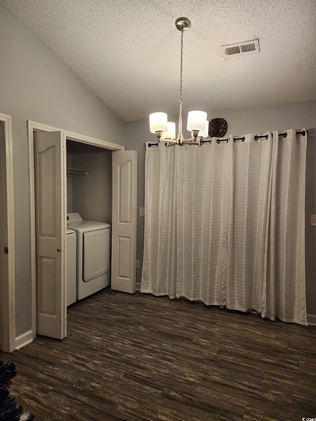 unfurnished dining area featuring a notable chandelier, lofted ceiling, dark wood-type flooring, and washing machine and clothes dryer