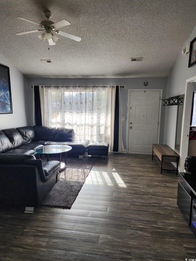 living room featuring a textured ceiling, ceiling fan, and dark wood-type flooring