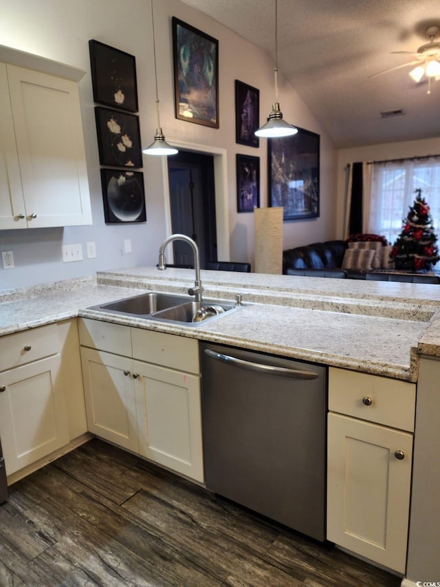 kitchen with pendant lighting, lofted ceiling, sink, stainless steel dishwasher, and a textured ceiling