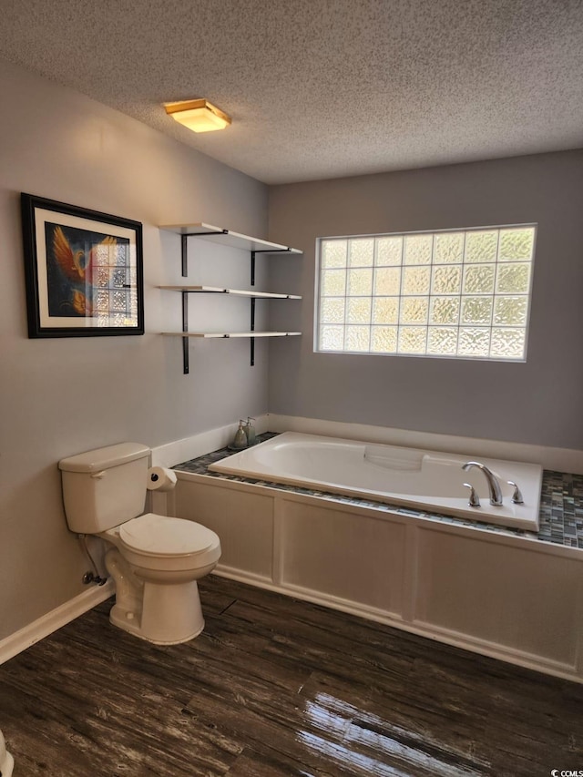 bathroom featuring a bath, wood-type flooring, a textured ceiling, and toilet