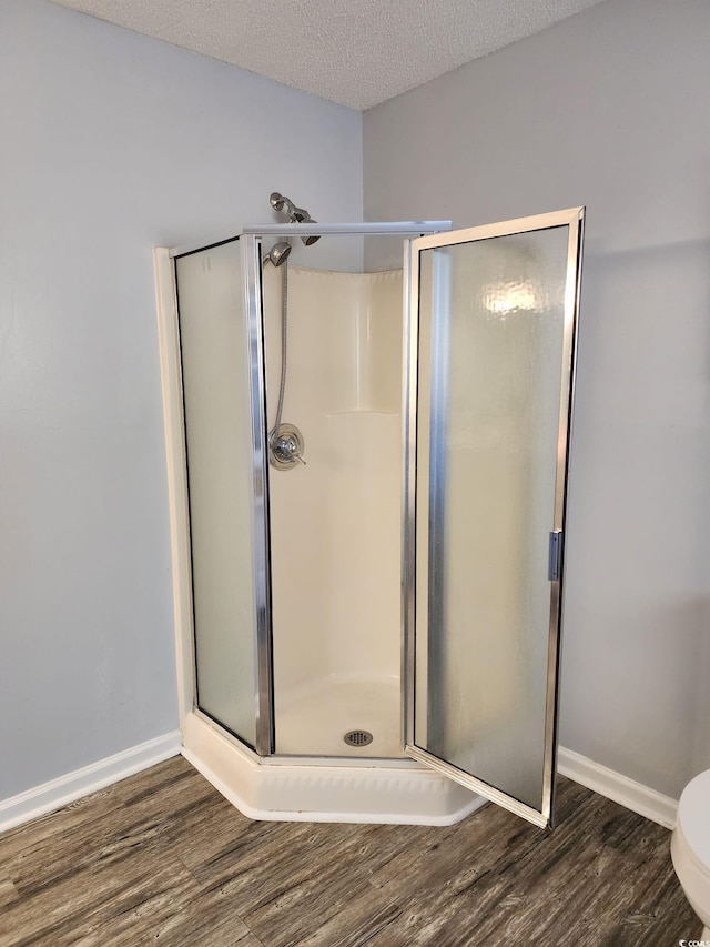 bathroom featuring hardwood / wood-style floors, an enclosed shower, and a textured ceiling