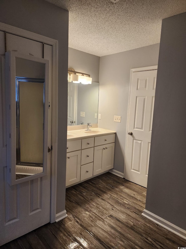 bathroom with a textured ceiling, vanity, and wood-type flooring