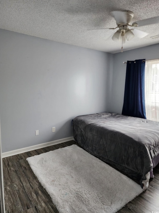 unfurnished bedroom featuring ceiling fan, dark hardwood / wood-style floors, and a textured ceiling