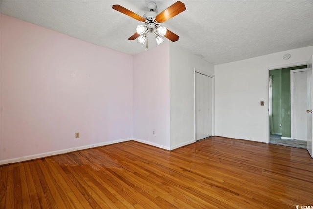 unfurnished room with a ceiling fan, a textured ceiling, baseboards, and hardwood / wood-style floors