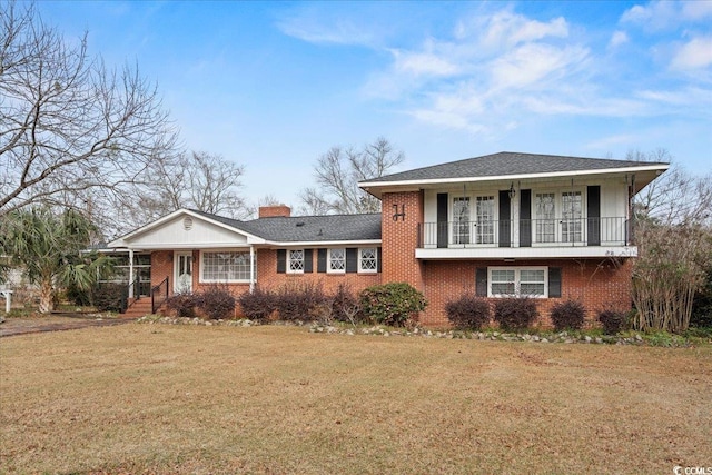 tri-level home with a front yard, brick siding, a chimney, and a balcony