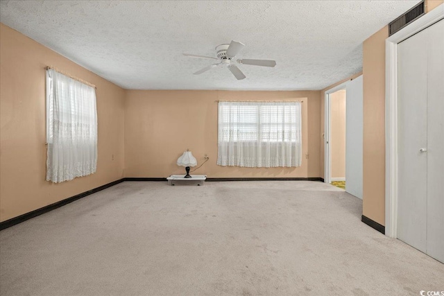 carpeted spare room featuring a ceiling fan, baseboards, visible vents, and a textured ceiling