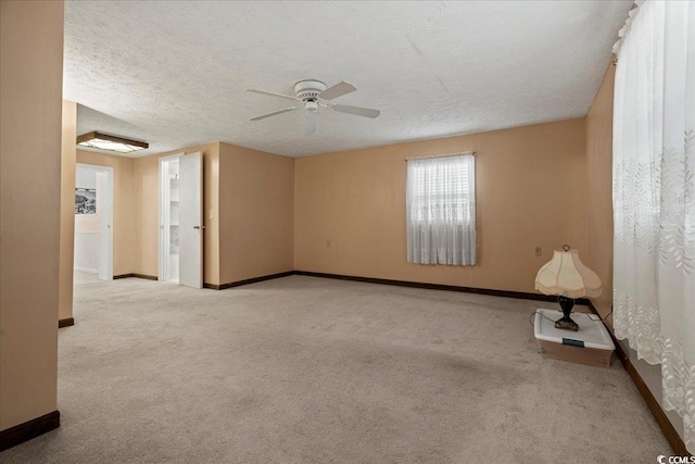 carpeted spare room featuring a ceiling fan, baseboards, and a textured ceiling