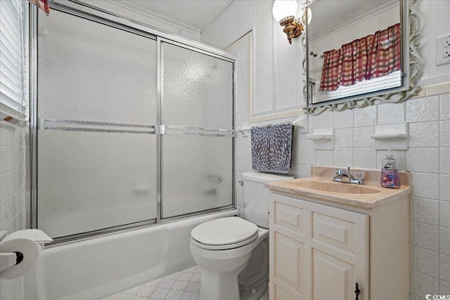 full bath featuring toilet, bath / shower combo with glass door, vanity, and tile walls