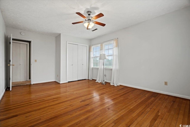 unfurnished bedroom featuring a textured ceiling, baseboards, and hardwood / wood-style flooring