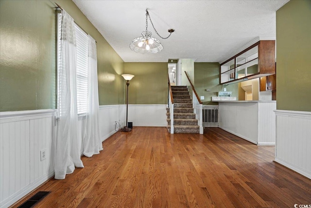 interior space with stairway, wainscoting, wood finished floors, and visible vents