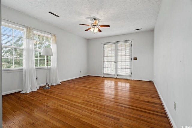 spare room featuring ceiling fan, a textured ceiling, wood finished floors, and visible vents