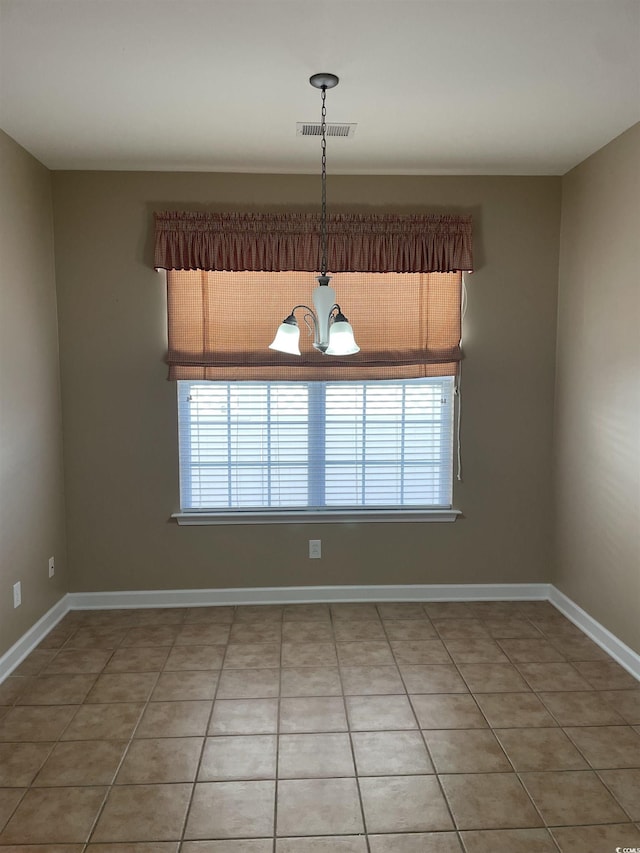 tiled spare room with plenty of natural light and a chandelier