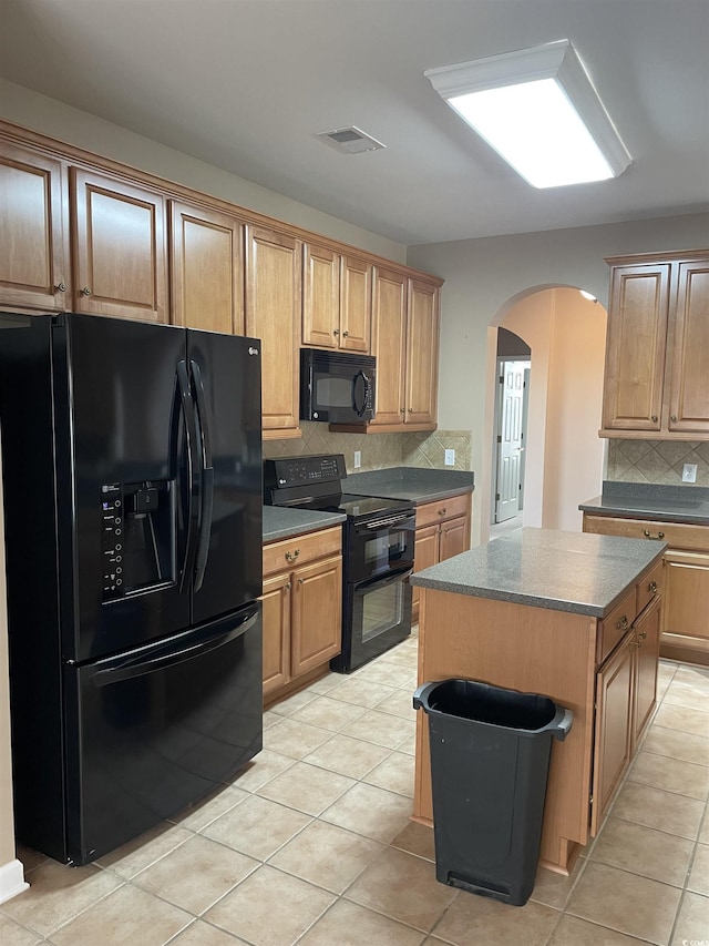 kitchen featuring decorative backsplash, a kitchen island, black appliances, and light tile patterned floors