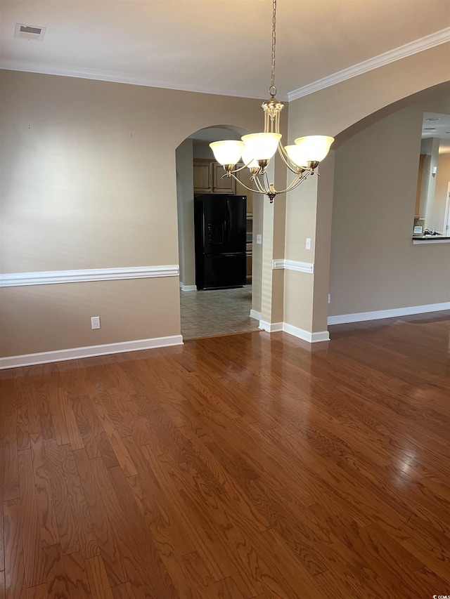 empty room with hardwood / wood-style floors, ornamental molding, and a chandelier