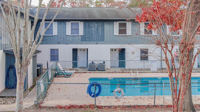 view of front of house with a community pool and central AC