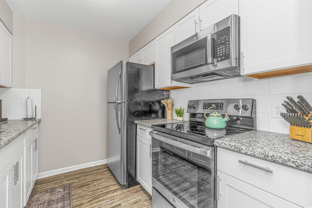 kitchen with decorative backsplash, light stone countertops, white cabinetry, and stainless steel appliances