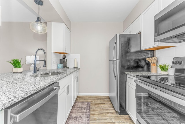 kitchen with appliances with stainless steel finishes, backsplash, white cabinetry, and light stone counters