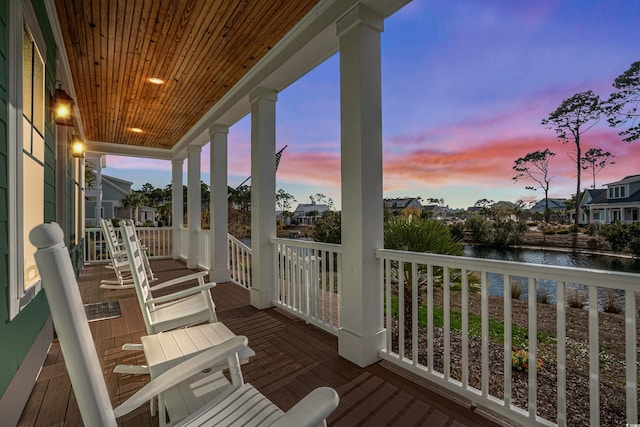 deck at dusk with a porch and a water view