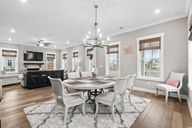 dining space with hardwood / wood-style flooring, plenty of natural light, a large fireplace, and ornamental molding