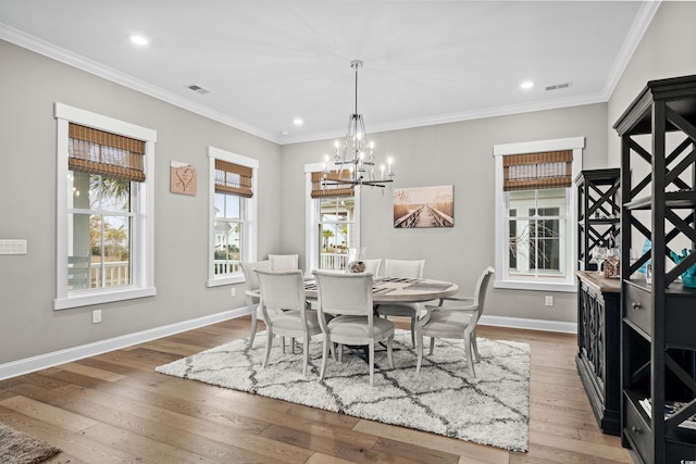 dining space with hardwood / wood-style floors, ornamental molding, and a notable chandelier