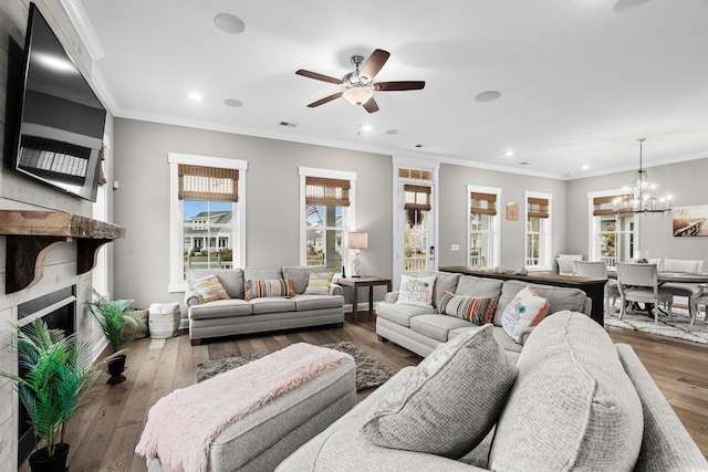 living room with hardwood / wood-style floors, ceiling fan with notable chandelier, ornamental molding, and a high end fireplace