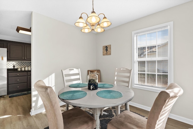 dining room featuring a chandelier, baseboards, and wood finished floors