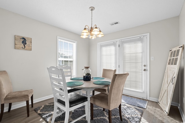 dining area featuring baseboards, wood finished floors, visible vents, and a chandelier