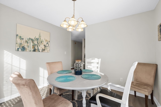 dining room featuring a chandelier, baseboards, and wood finished floors