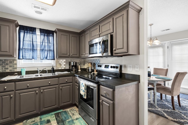 kitchen with dark countertops, visible vents, gray cabinets, appliances with stainless steel finishes, and a sink