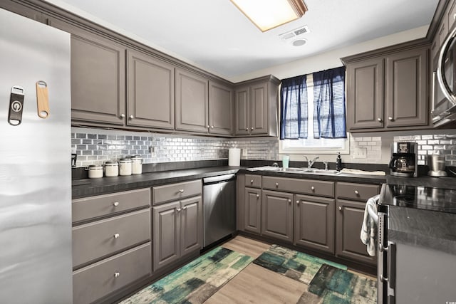 kitchen featuring dark countertops, visible vents, light wood finished floors, appliances with stainless steel finishes, and a sink