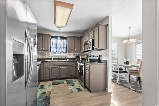 kitchen with light wood-style flooring, gray cabinetry, decorative backsplash, stainless steel appliances, and dark countertops