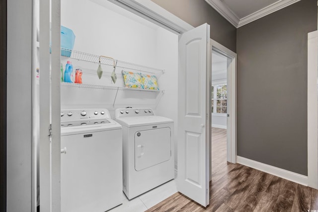 laundry room featuring hardwood / wood-style flooring, washing machine and dryer, and crown molding