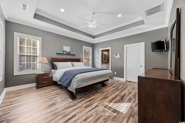 bedroom with a raised ceiling, ceiling fan, crown molding, and light wood-type flooring