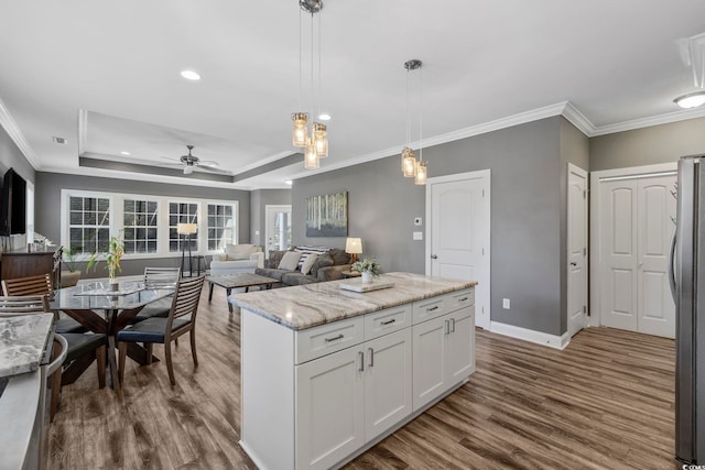 kitchen featuring a center island, white cabinets, a raised ceiling, ceiling fan, and decorative light fixtures