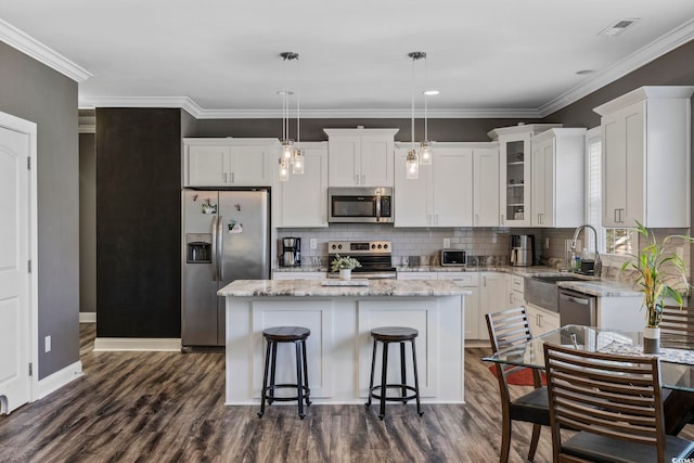 kitchen with white cabinets, pendant lighting, a center island, and stainless steel appliances