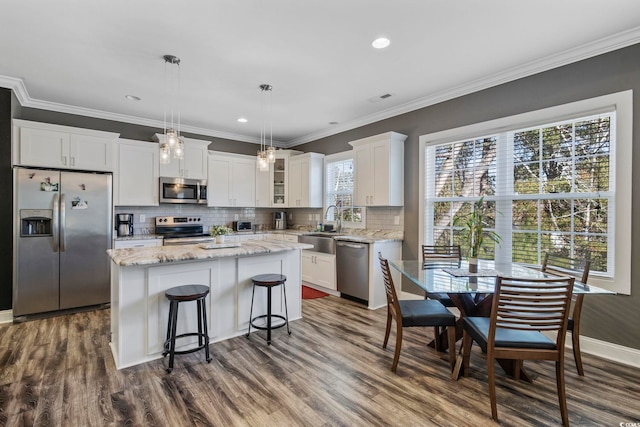 kitchen featuring white cabinetry, a center island, dark hardwood / wood-style floors, pendant lighting, and appliances with stainless steel finishes