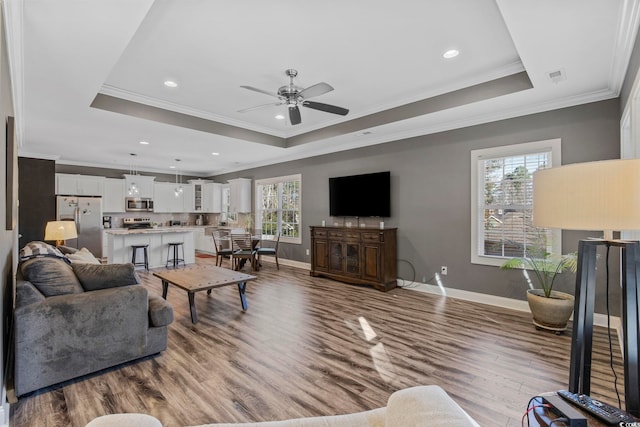 living room featuring a tray ceiling, hardwood / wood-style flooring, and crown molding