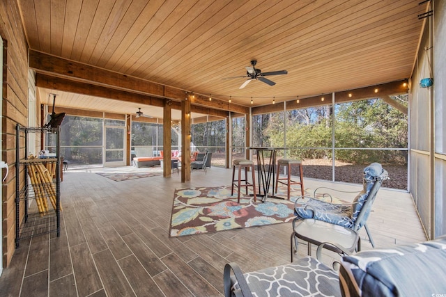 unfurnished sunroom featuring ceiling fan, plenty of natural light, and wood ceiling