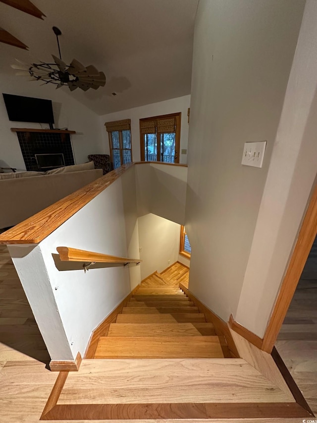 stairway featuring ceiling fan and a brick fireplace