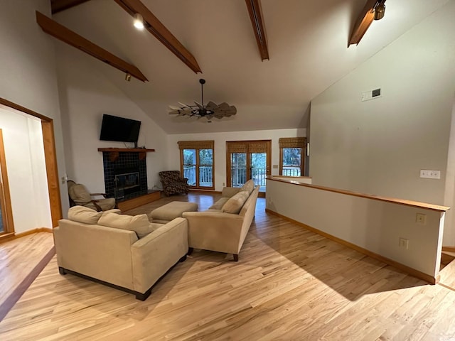 living room featuring vaulted ceiling with beams, ceiling fan, a fireplace, and light hardwood / wood-style flooring