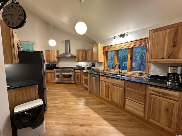 kitchen featuring tasteful backsplash, stainless steel appliances, sink, wall chimney range hood, and hanging light fixtures