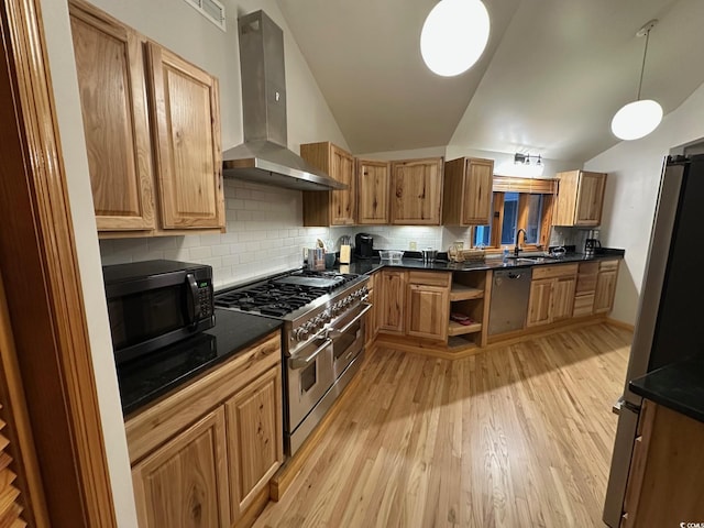 kitchen with lofted ceiling, pendant lighting, stainless steel appliances, and wall chimney range hood