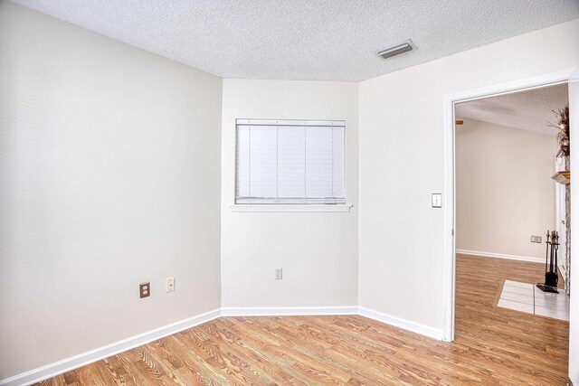 empty room with a textured ceiling and light wood-type flooring